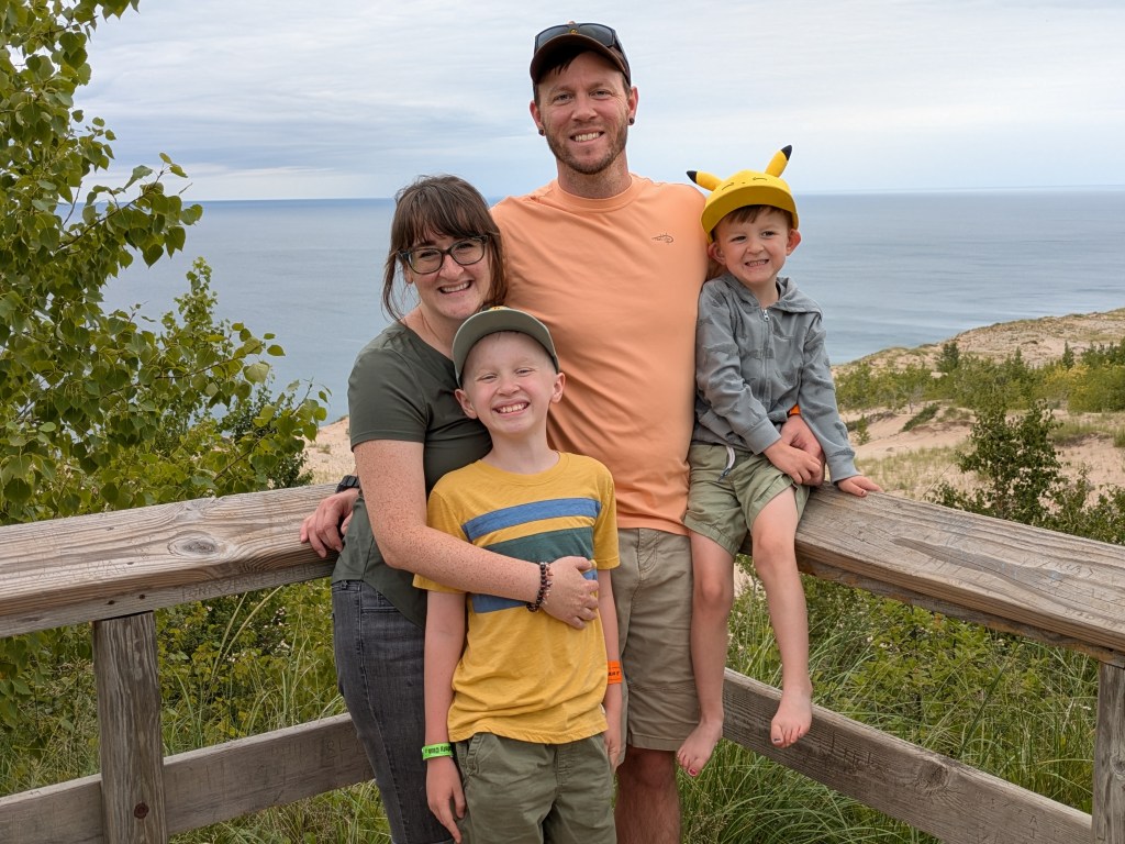 Picture of a very handsome family standing in front of a beach. 